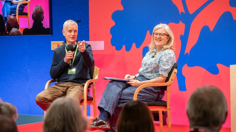 Two National Trust colleagues sat on a stage discussing topics at the AGM in 2024